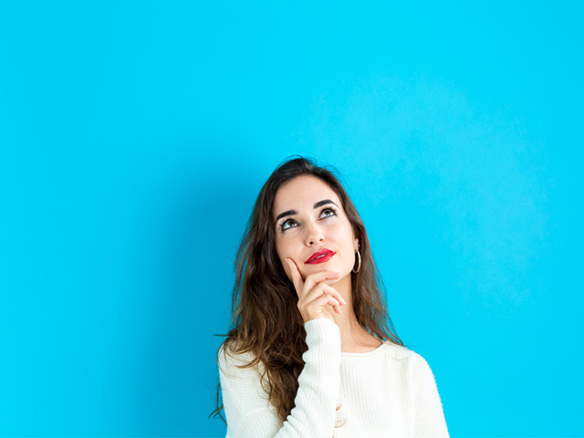 woman looking up thinking in front of blue background